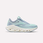 The Women's Fuel Flex Run Shoes by Reebok feature a light blue and mint green design with a thick white sole and oval cutouts, built for long-lasting comfort, shown from the side on a plain white background.