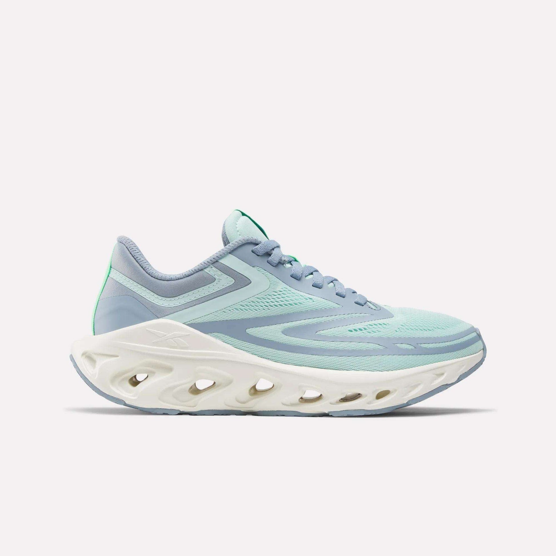The Women's Fuel Flex Run Shoes by Reebok feature a light blue and mint green design with a thick white sole and oval cutouts, built for long-lasting comfort, shown from the side on a plain white background.