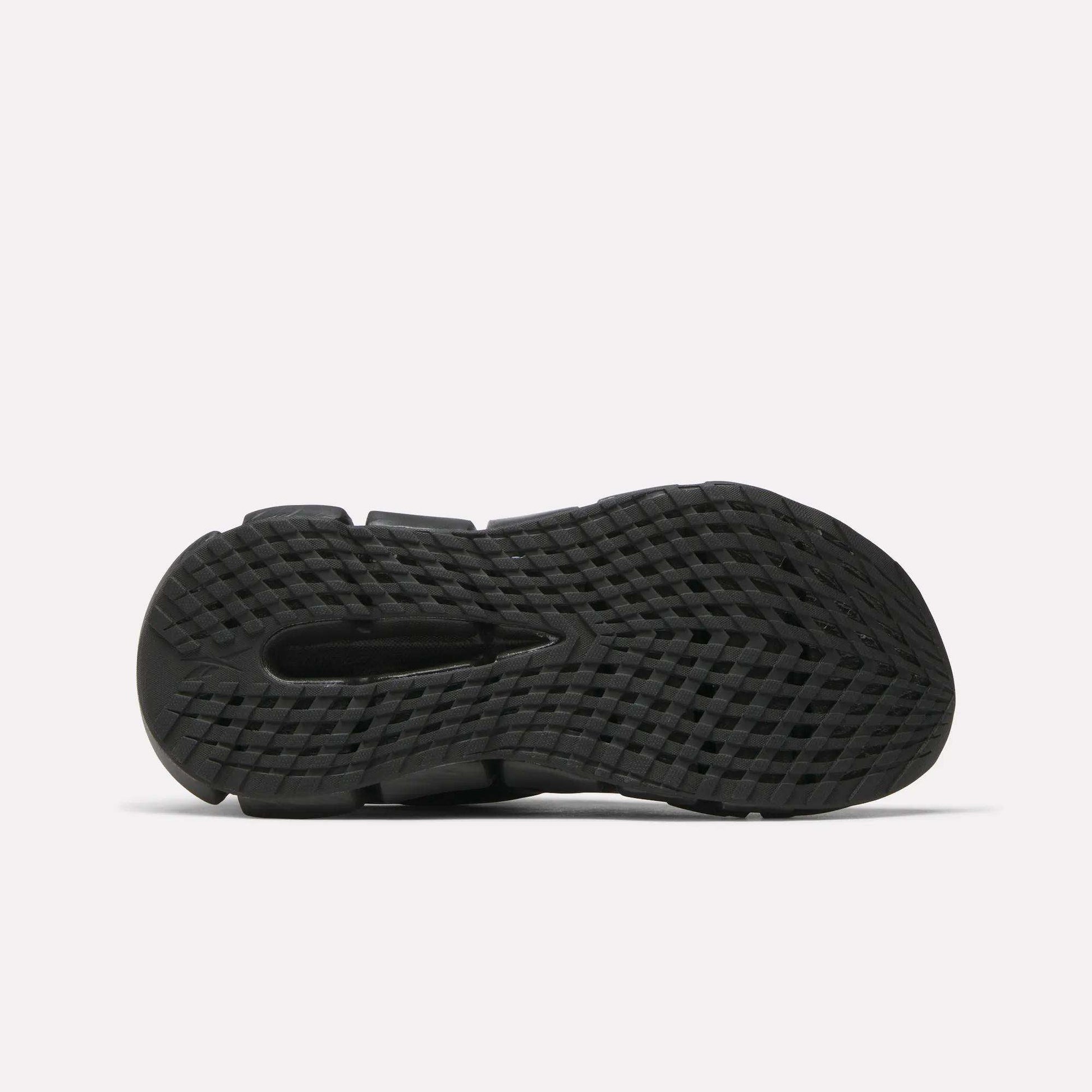 The image shows the bottom view of the Reebok Women's FloatZig 2 Running Shoes' black sole, featuring a textured, grid-like pattern and traction grooves with energy-returning Superfloat+ cushioning, set against a plain white background.