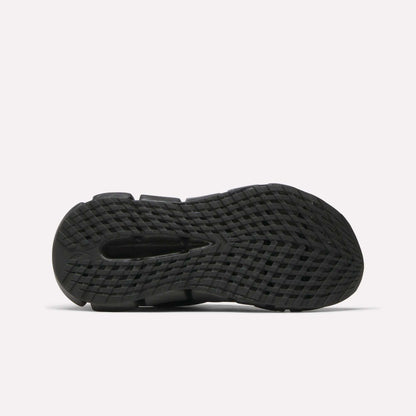 The image shows the bottom view of the Reebok Women's FloatZig 2 Running Shoes' black sole, featuring a textured, grid-like pattern and traction grooves with energy-returning Superfloat+ cushioning, set against a plain white background.