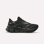The Reebok Women's FloatZig 2 Running Shoes feature a black mesh upper, sleek design, and chunky segmented sole with Superfloat+ cushioning for energy return, shown in a side view against a white background.