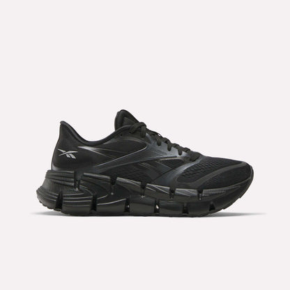The Reebok Women's FloatZig 2 Running Shoes feature a black mesh upper, sleek design, and chunky segmented sole with Superfloat+ cushioning for energy return, shown in a side view against a white background.