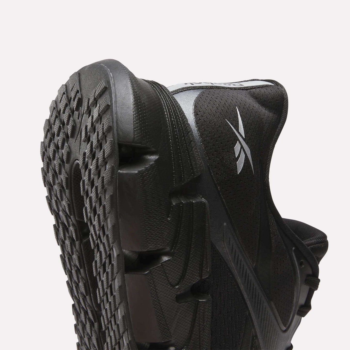 Close-up of Reebok Men's FloatZig 2 Running Shoes in black, featuring a textured rubber sole, energy-returning cushioning, and a white Reebok logo on the side, set against a plain light background.