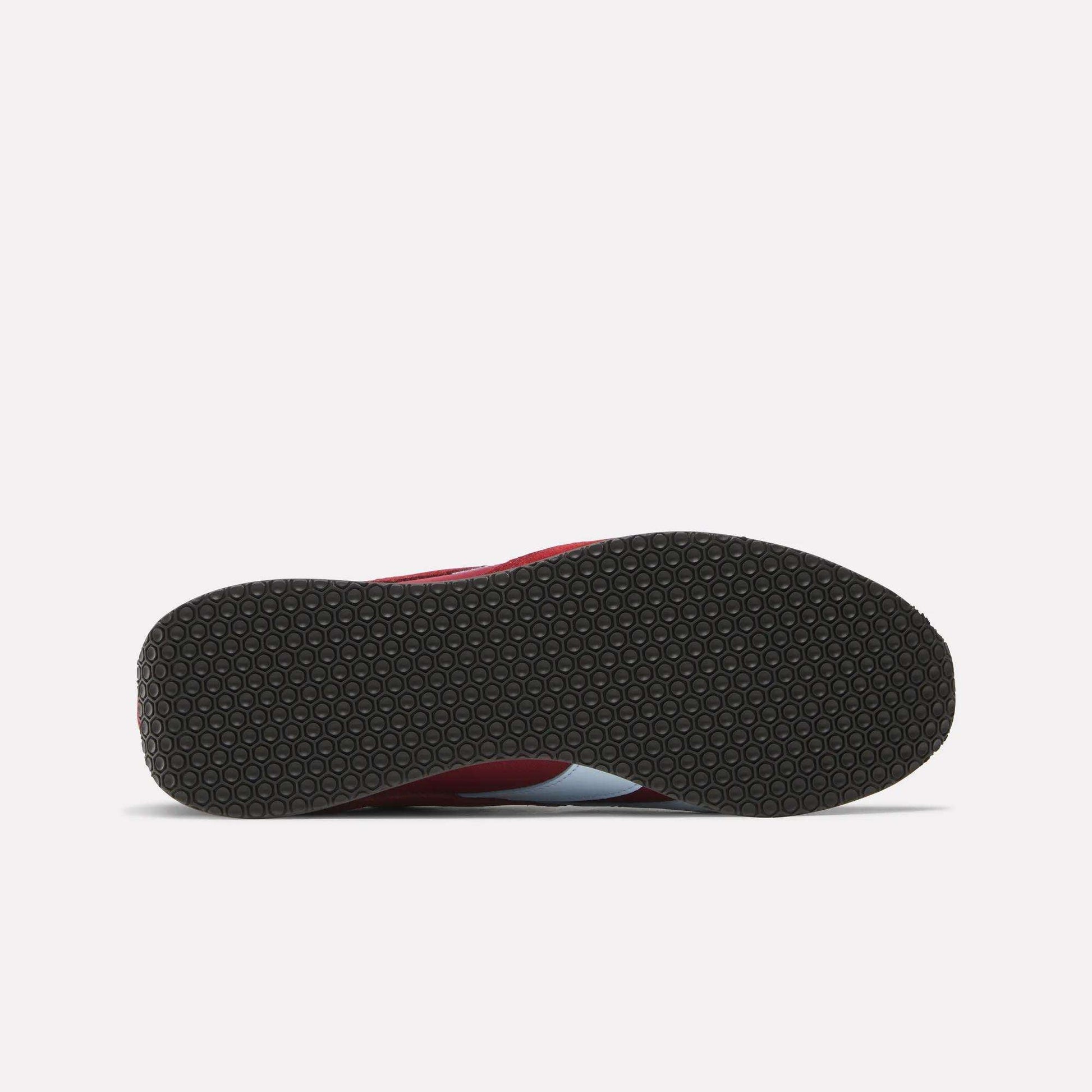 The image shows the bottom view of Reebok R400 Shoes with a black, textured circular rubber sole, and a glimpse of the red and white upper.