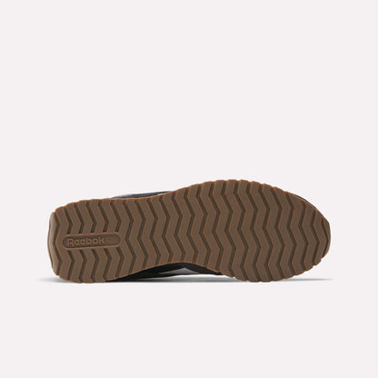 A brown rubber sole of the Reebok Classic AZ Shoes is shown from the bottom, featuring a zigzag tread pattern and the Reebok logo embossed near the heel, inspired by '70s retro running styles, against a plain white background.