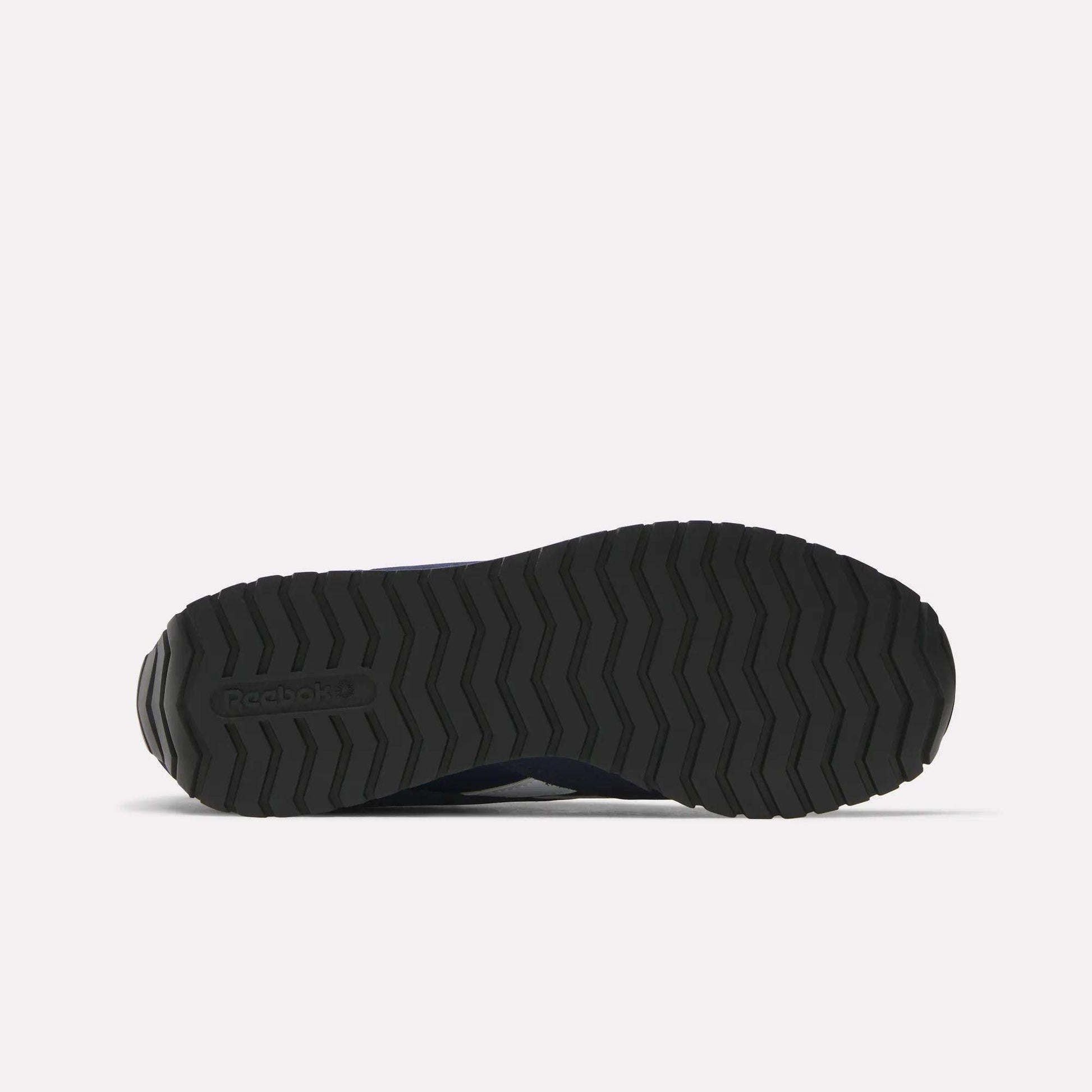 The image displays the bottom view of a black Reebok Classic AZ Shoes sole, featuring a zigzag tread pattern inspired by retro running shoes, all set against a plain white background.