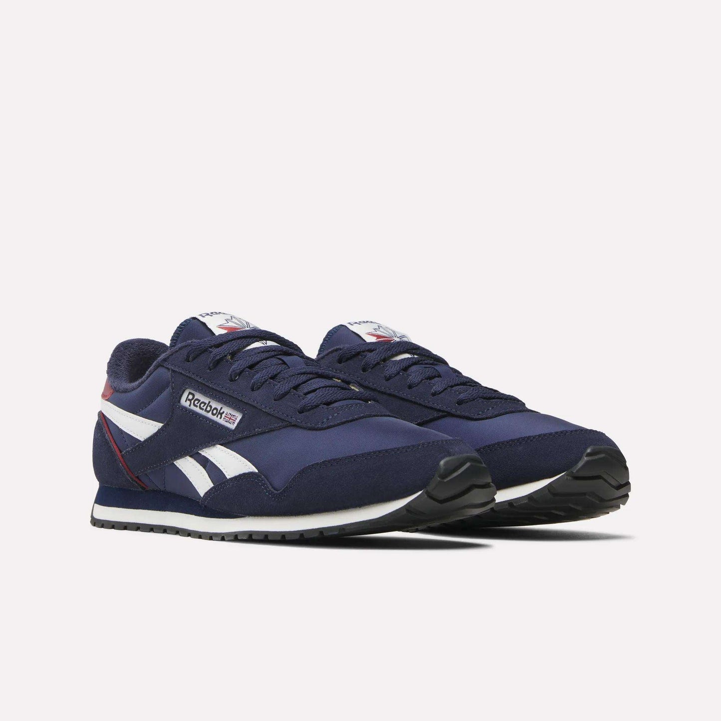 The Reebok Classic AZ Shoes are navy blue retro runners with white and red accents, 70s-inspired side stripes, black outsoles, and the Reebok logo on the side and tongue. The shoes appear angled slightly to the right.