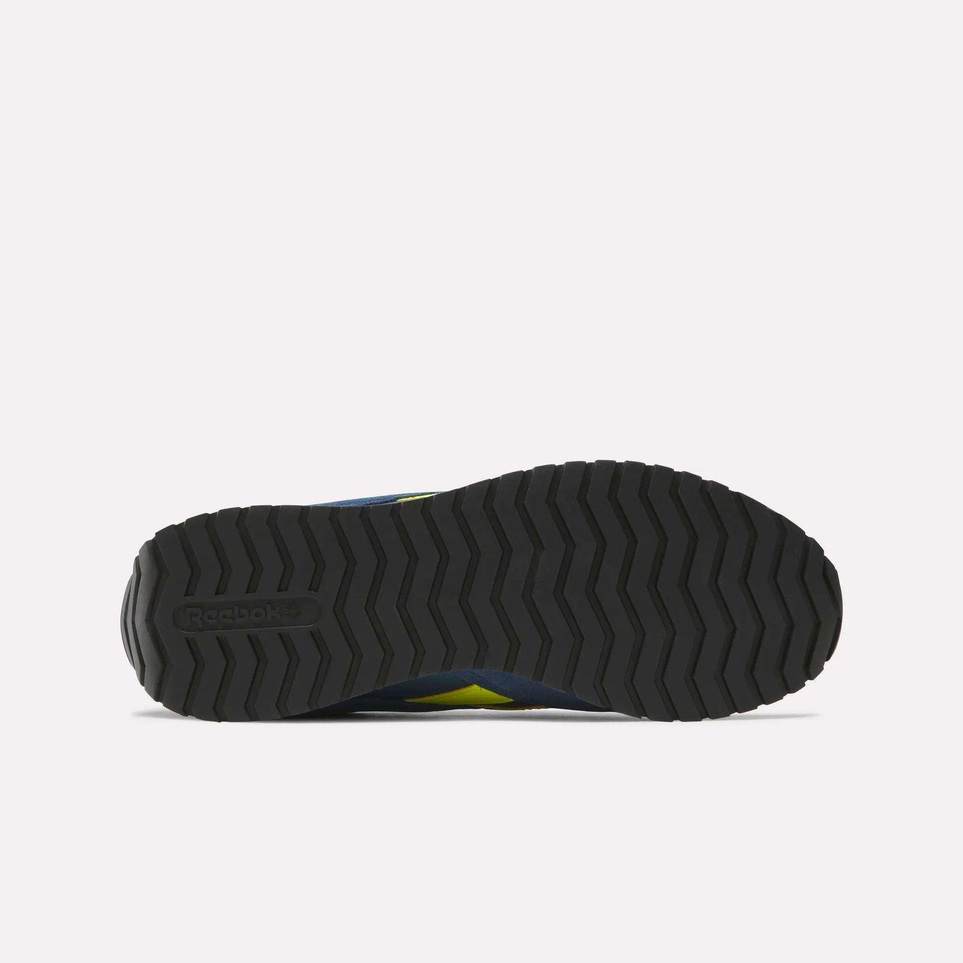 Bottom view of a black Reebok Classic AZ Shoes outsole, showing a zigzag tread inspired by '70s retro running shoes and the embossed Reebok logo on the heel, all set against a plain white background.