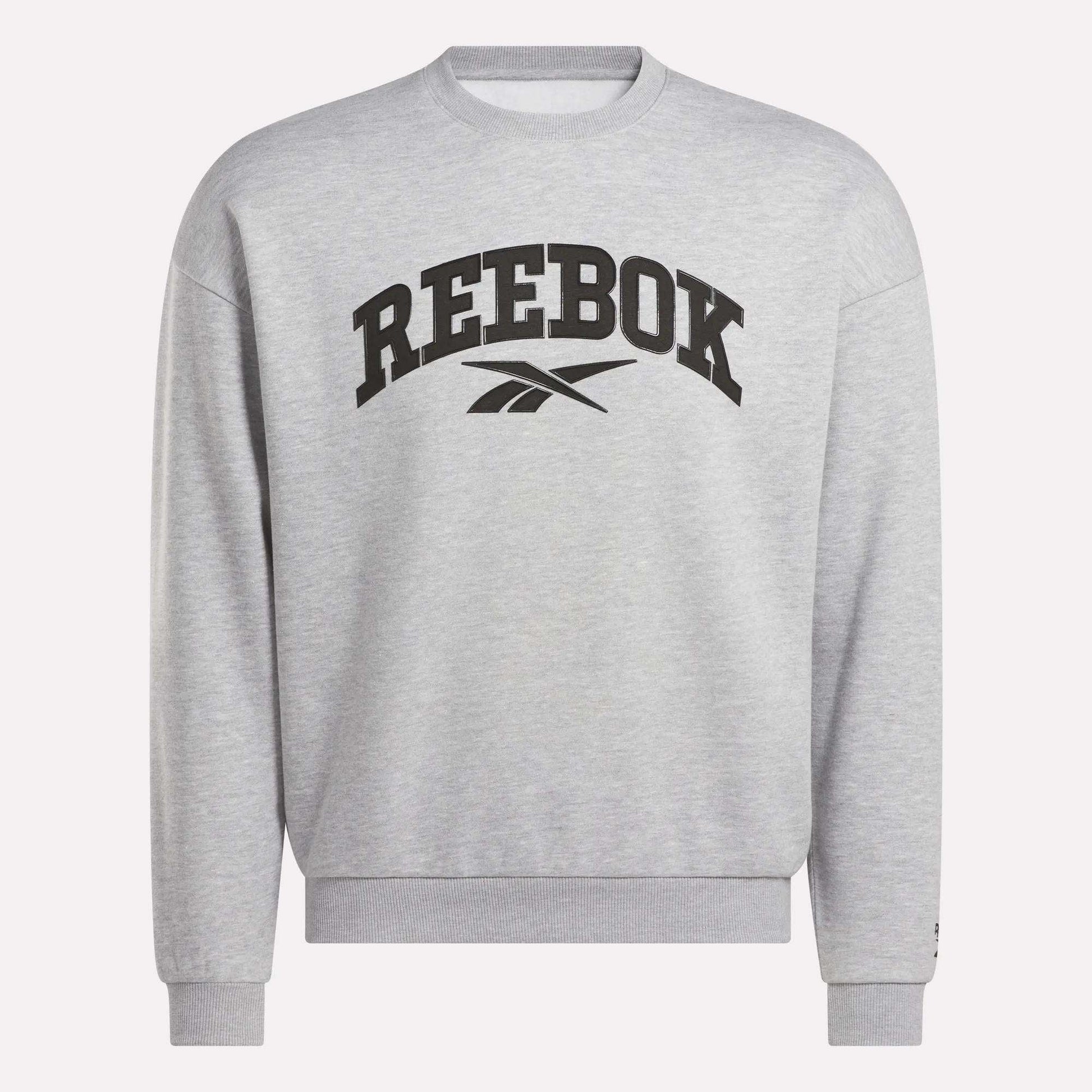 The Reebok Men's Cottle Sweatshirt is light grey with a black Reebok logo and brand name on the chest. This crewneck features long sleeves, ribbed cuffs and hem, and provides a relaxed, casual fit.