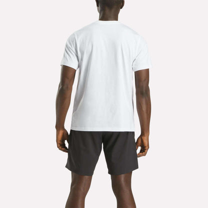 A man is facing away from the camera, wearing a Reebok Men's Big Logo Crewneck Short Sleeve Tee in white and black shorts, set against a light background.