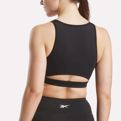 A woman wears the Reebok Women's Core High-Impact Bra with a cutout back and matching sweat-wicking leggings, shown from behind against a plain white background.