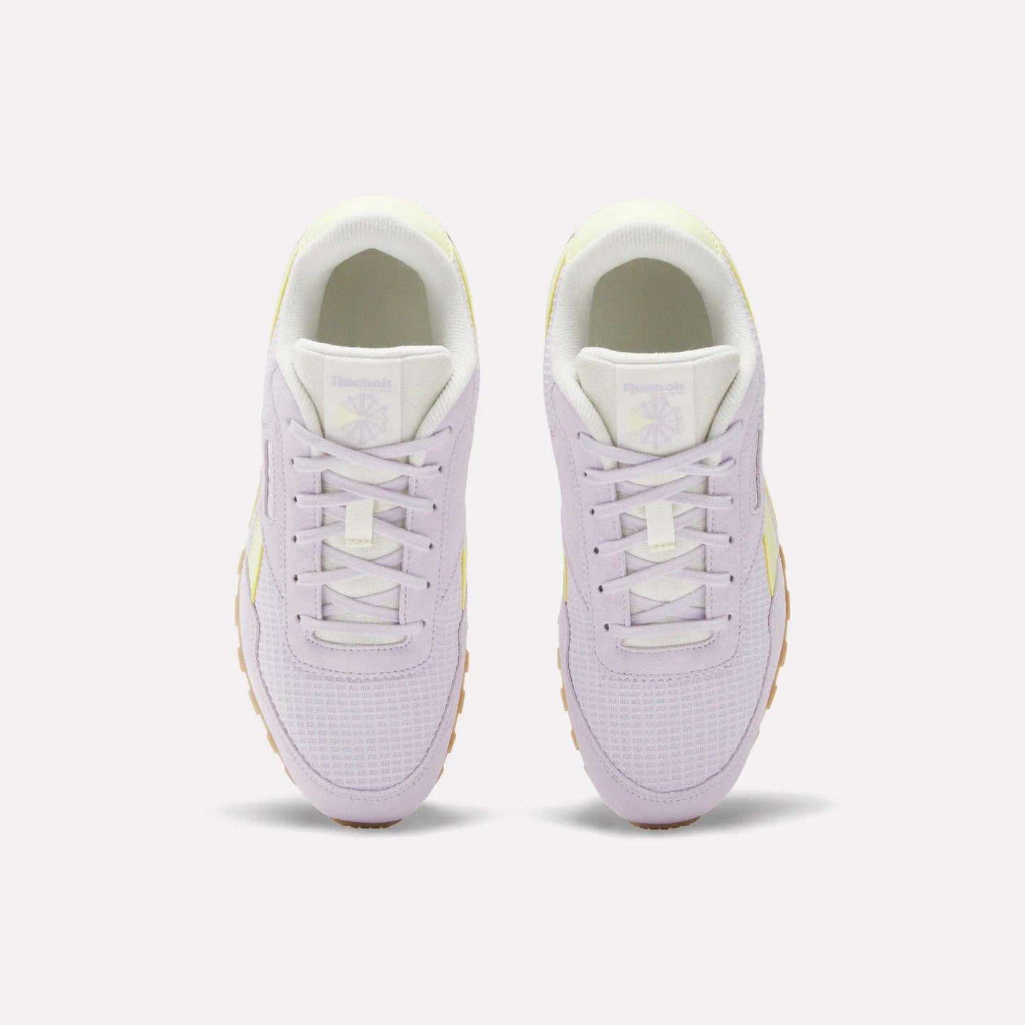 A pair of Reebok Classic AZ Shoes for big kids in pastel purple, shown from above with white laces, white tongues, and gum-colored soles. Heritage running style meets modern comfort on a plain light background.