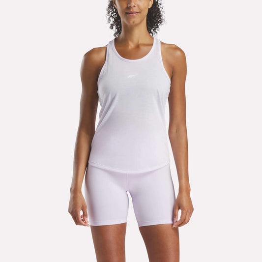 A person wears a slim, sweat-wicking Reebok Women's Core Tank Top with matching white shorts, facing forward against a plain background.