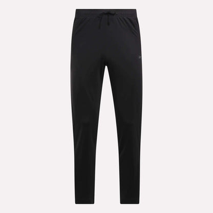 Reebok Men's Train Knit Pants shown in black with a slim fit, elastic waistband, and drawstring. These minimalistic pants are ideal for workouts or casual wear, displayed against a light plain background.