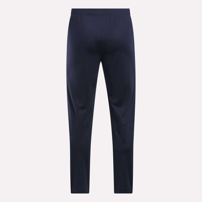 Men's Train Knit Pants by Reebok in navy blue, featuring an elastic waistband, displayed flat and facing forward against a plain light background.