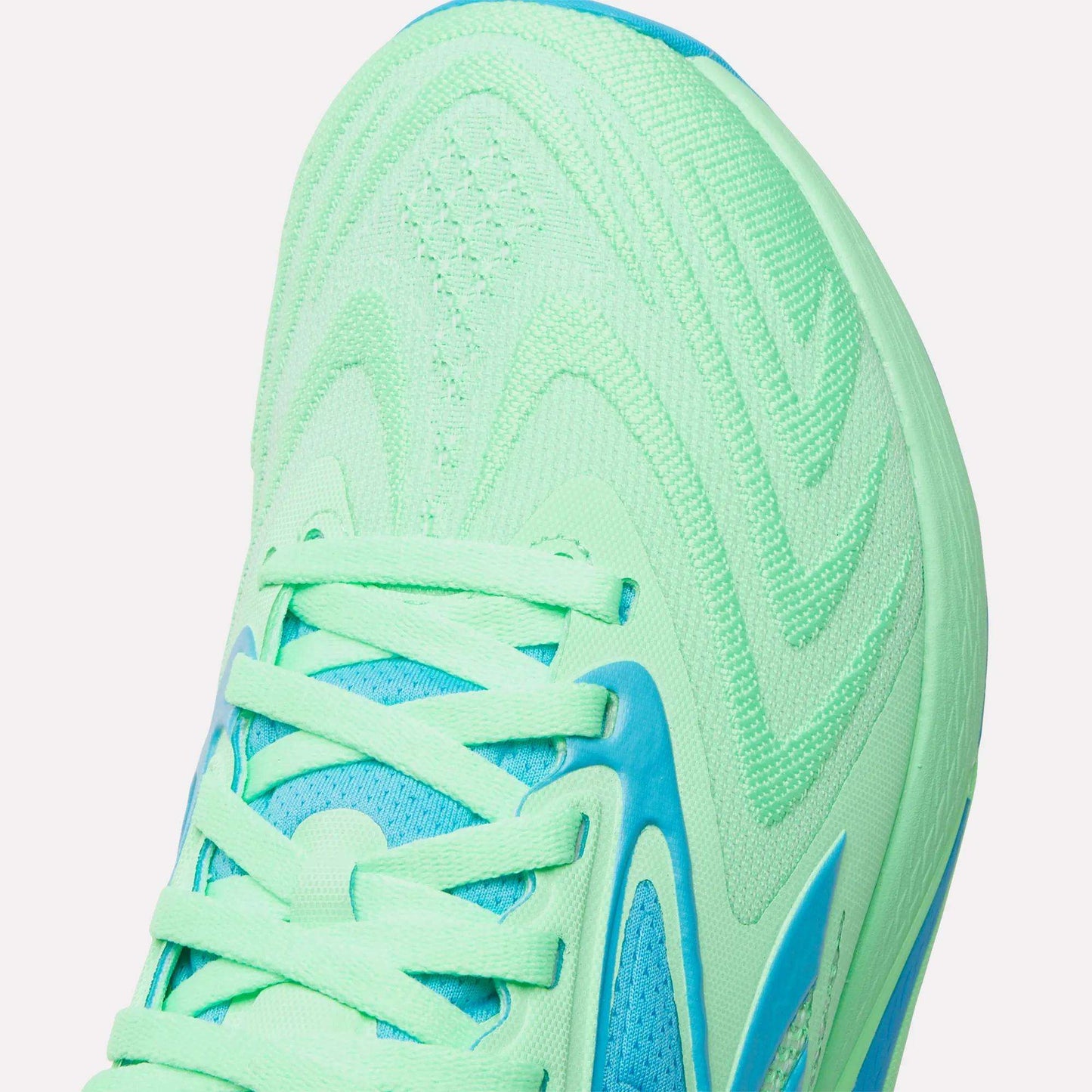 Close-up of the toe and laces of mint green Reebok Women's Nano X5 Edge Training Shoes with blue accents and textured patterns—ideal for your next HIIT workout.