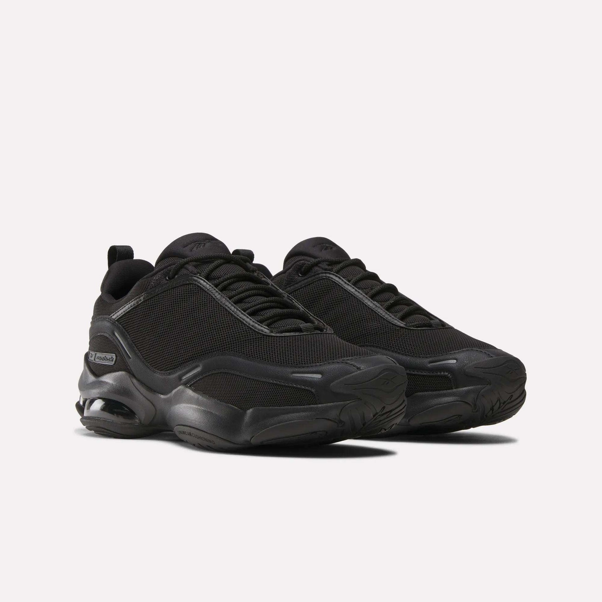 The Reebok DMX Series 3000 Shoes in black feature mesh uppers, thick rubber soles, subtle side branding, and DMX moving air technology for enhanced comfort—shown on a plain white background.