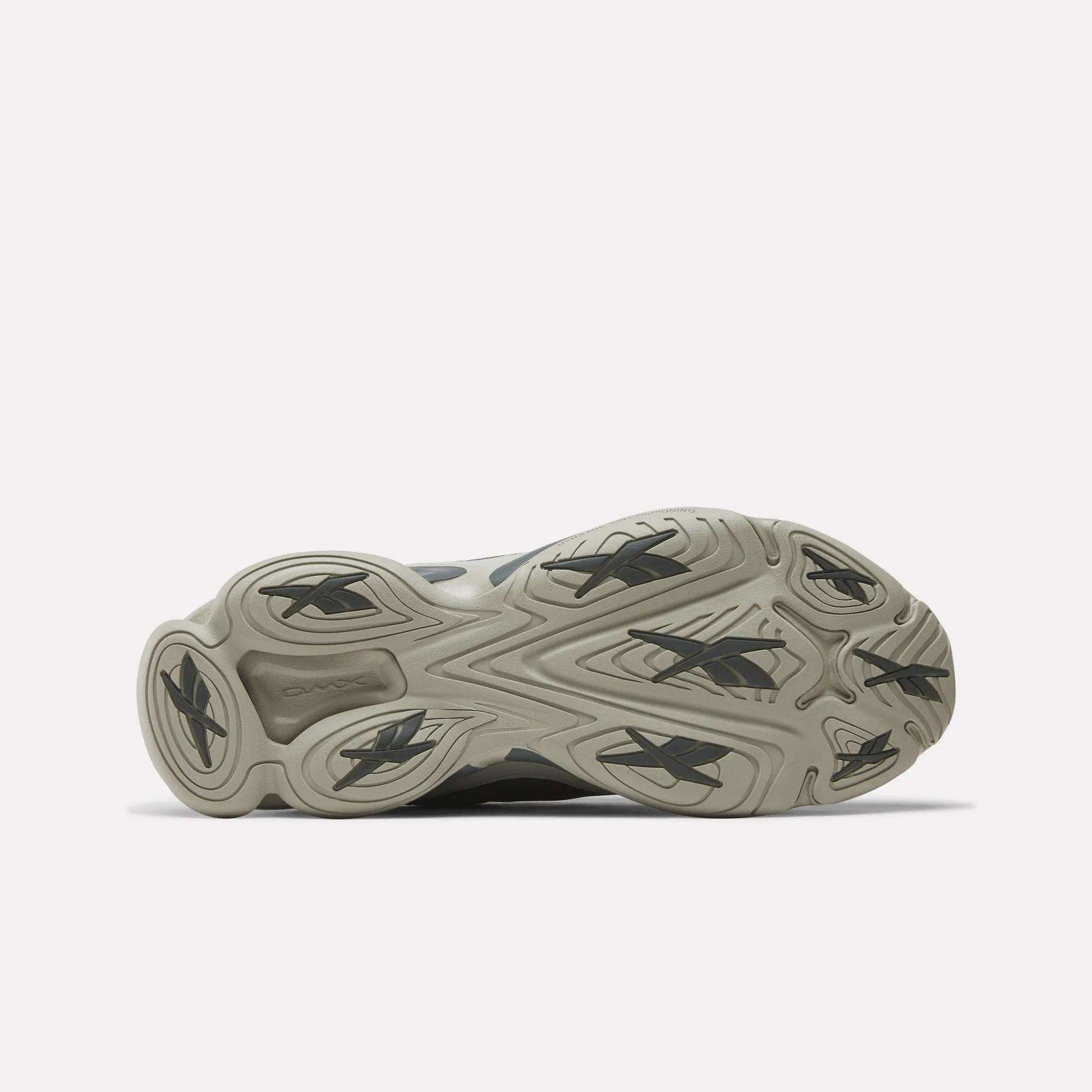 Bottom view of Reebok DMX Series 3000 Shoes with a light gray rubber outsole, multiple black Reebok logos, and a wavy tread pattern for traction and comfort, highlighting the brand’s innovative design.