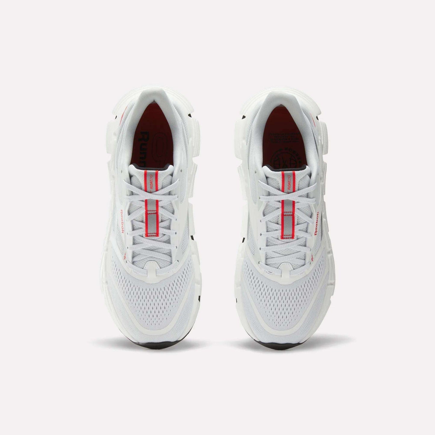 A pair of Reebok Men's FloatZig 2 Running Shoes in white, shown from above with red accents on the tongue and mesh details on the toe, placed side by side on a plain light background.