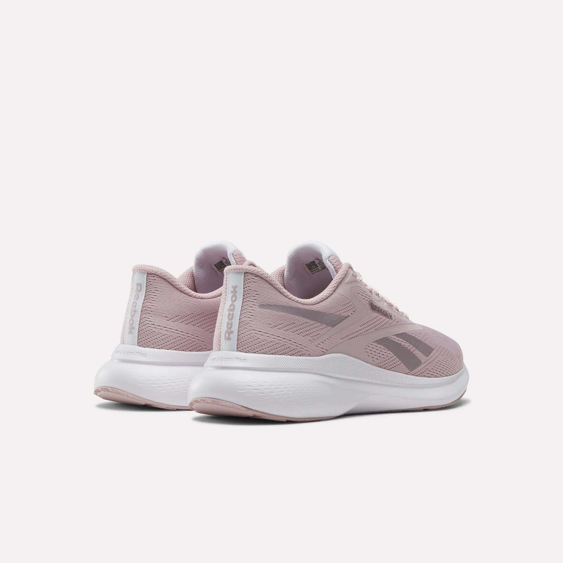 The Reebok Women's Energen Run 4 Running Shoes in light pink feature a breathable mesh upper and white soles, shown from back and side angles against a plain white background.