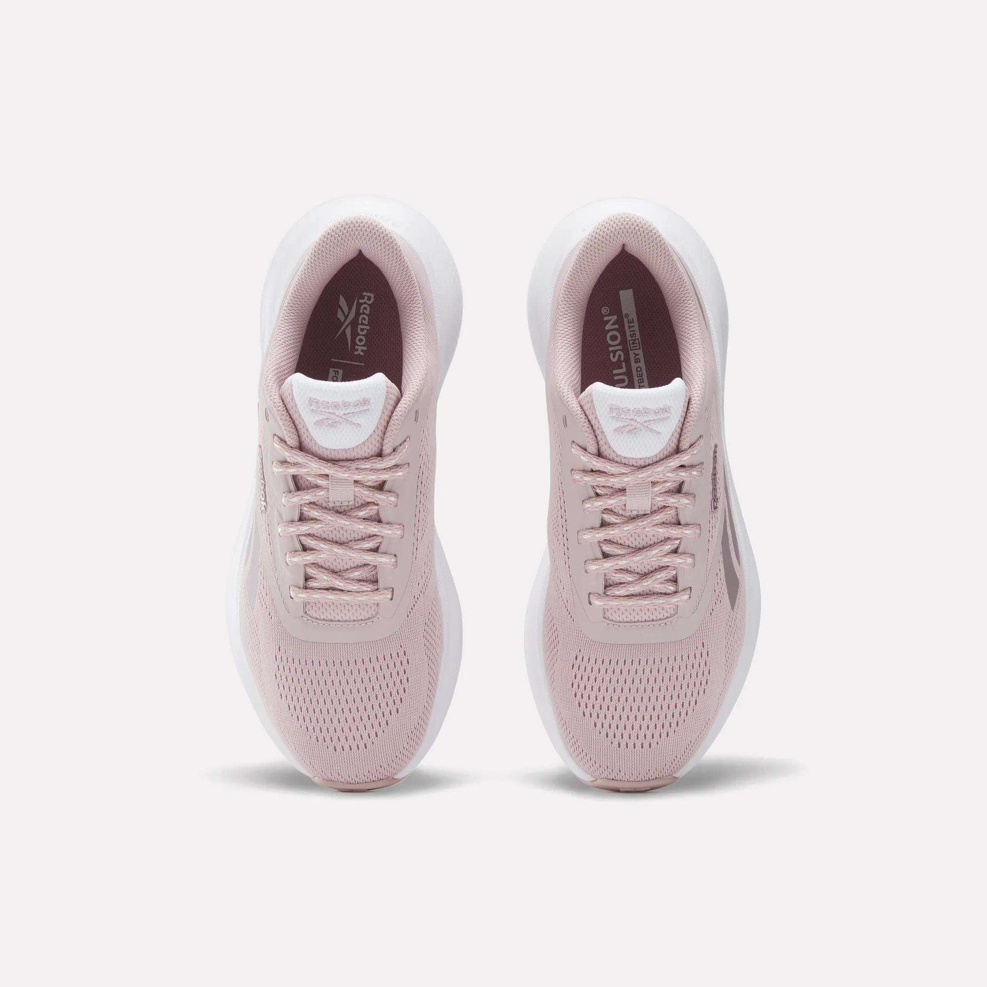 A pair of Women's Energen Run 4 Running Shoes by Reebok in light pink with white soles, viewed from above on a plain white background. These lightweight shoes have a breathable mesh upper, laces, and Reebok branding on the tongue and insole.