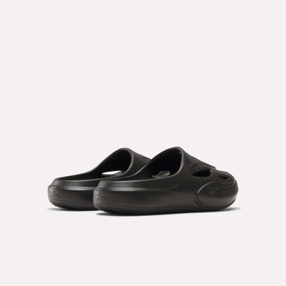 A pair of DMX Recovery Mules by Reebok, black with molded EVA construction, cut-out ventilation holes, and thick soles, displayed on a plain light background.