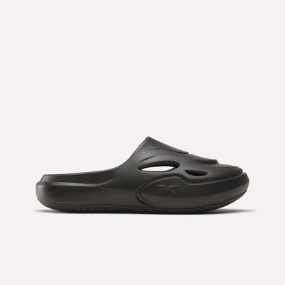 The Reebok DMX Recovery Mules are black slip-on shoes made from molded EVA, with cutout vents on the upper, a closed toe, and a chunky sole. Shown in side profile against a plain white background.