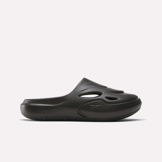 The Reebok DMX Recovery Mules are black slip-on shoes made from molded EVA, with cutout vents on the upper, a closed toe, and a chunky sole. Shown in side profile against a plain white background.