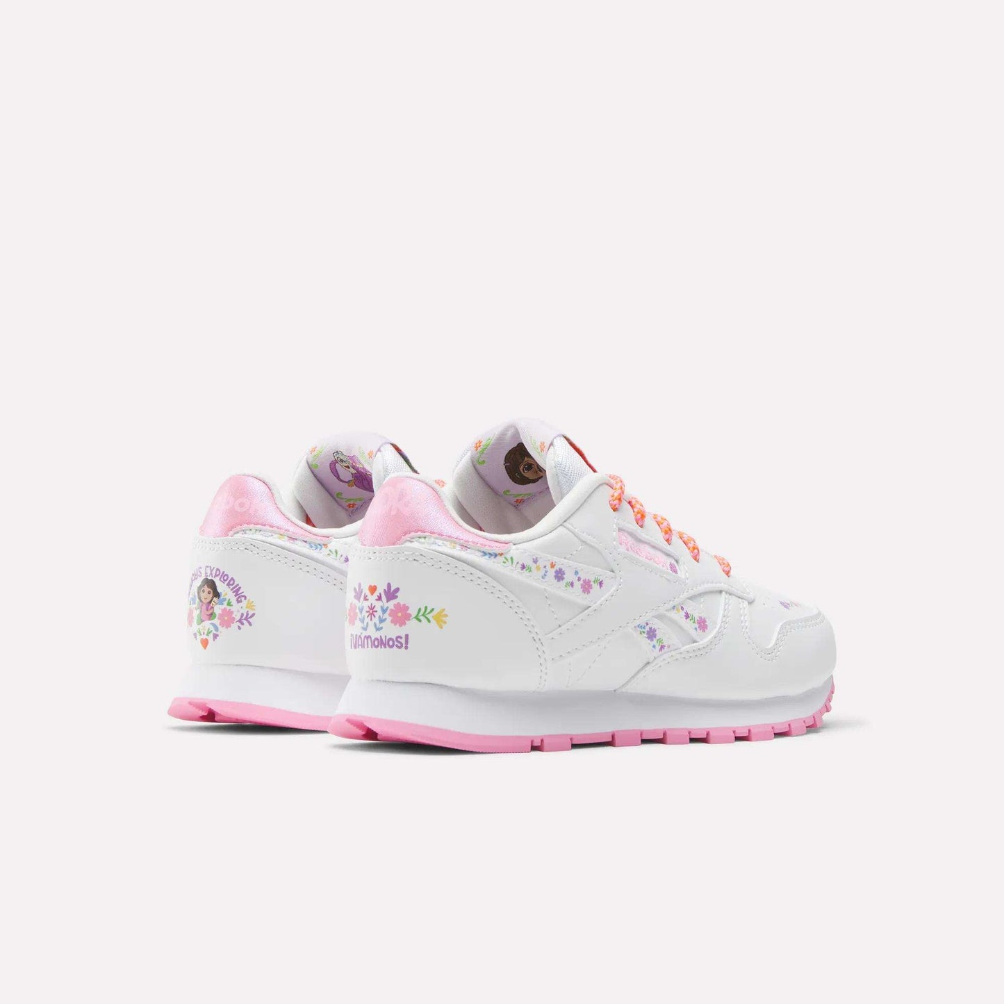 The Reebok x DORA Classic Leather Shoes for little kids feature a white design with pink soles and laces, floral graphics, and Dora the Explorer character details. These comfy Reebok shoes have a soft pink interior lining, perfect for young fans.
