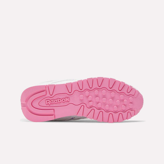 Bottom view of Reebok x DORA Classic Leather Shoes for little kids, showcasing a bright pink textured outsole with the Reebok logo near the heel. This vibrant style stands out against a plain white background—ideal for young sneaker fans.