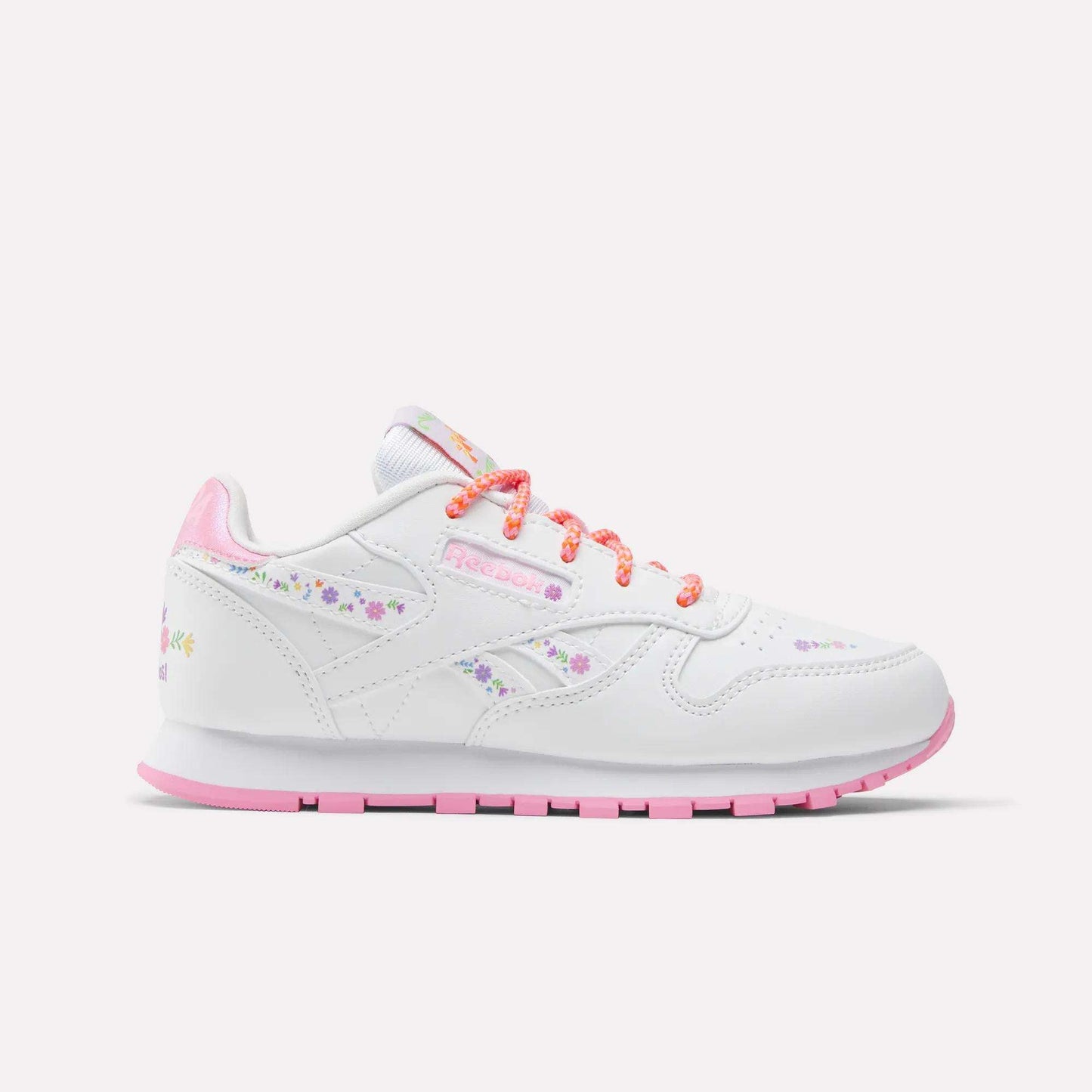 The Reebok x DORA Classic Leather Shoes for little kids feature white leather with pink accents, pastel floral designs, and colorful orange and pink laces—perfect comfy sneakers for young explorers. Shown against a plain light background.