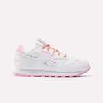 The Reebok x DORA Classic Leather Shoes for little kids feature white leather with pink accents, pastel floral designs, and colorful orange and pink laces—perfect comfy sneakers for young explorers. Shown against a plain light background.