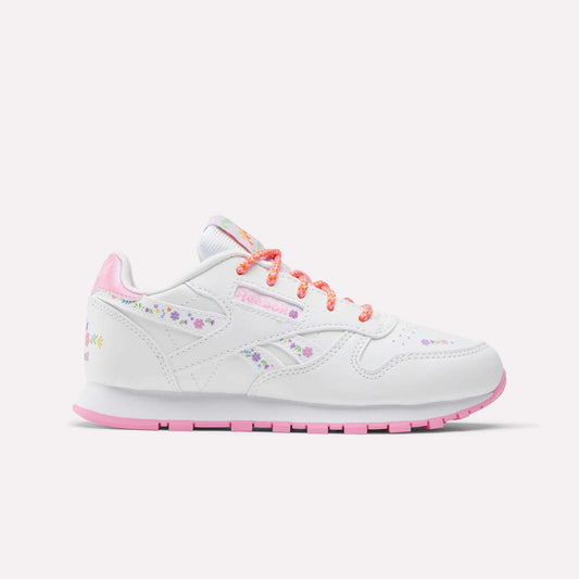 The Reebok x DORA Classic Leather Shoes for little kids feature white leather with pink accents, pastel floral designs, and colorful orange and pink laces—perfect comfy sneakers for young explorers. Shown against a plain light background.