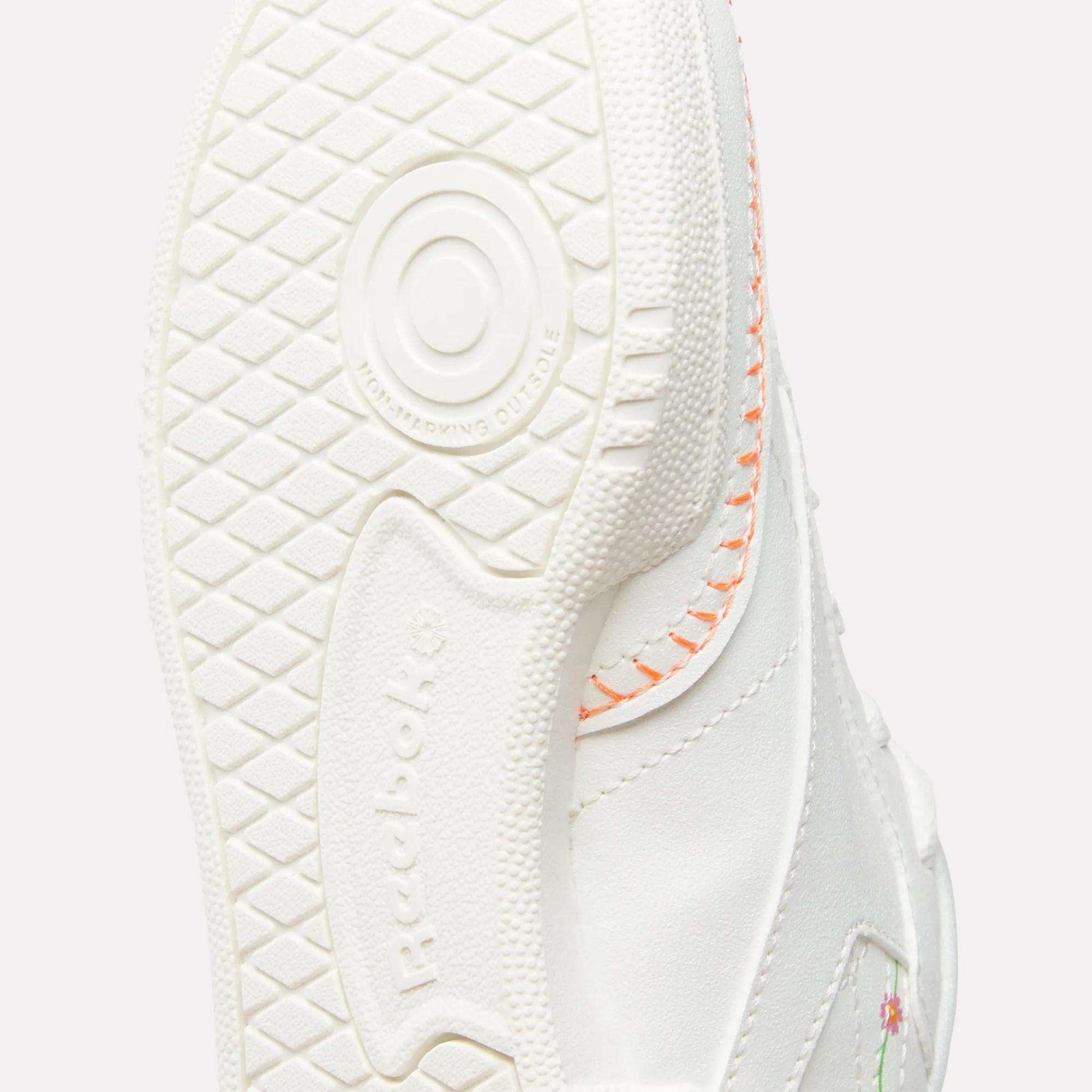 Close-up of the sole on Reebok x DORA Club C Shoes for little kids, showing textured grip, circular pattern, orange stitching, and a hint of a floral design on the upper.