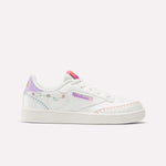 The Reebok x DORA Club C Shoes for little kids feature pastel rainbow accents, floral embroidery, a pink logo, and orange stitching on white—perfect colorful shoes by Reebok for playful style.