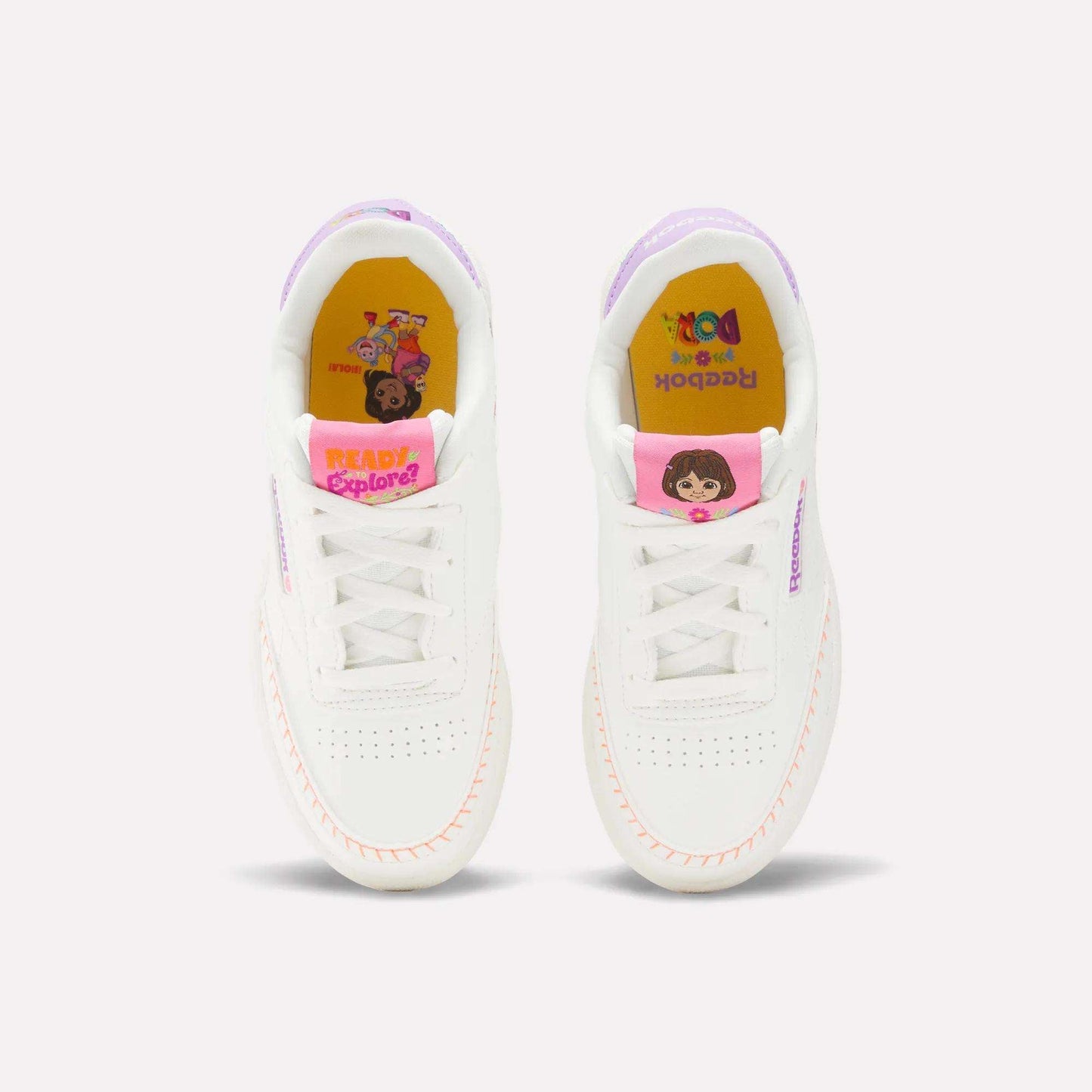The Reebok x DORA Club C Shoes for little kids feature white uppers with pink accents, fun Dora the Explorer and friends on yellow insoles, and “READY TO EXPLORE!” text—perfect for young adventurers.