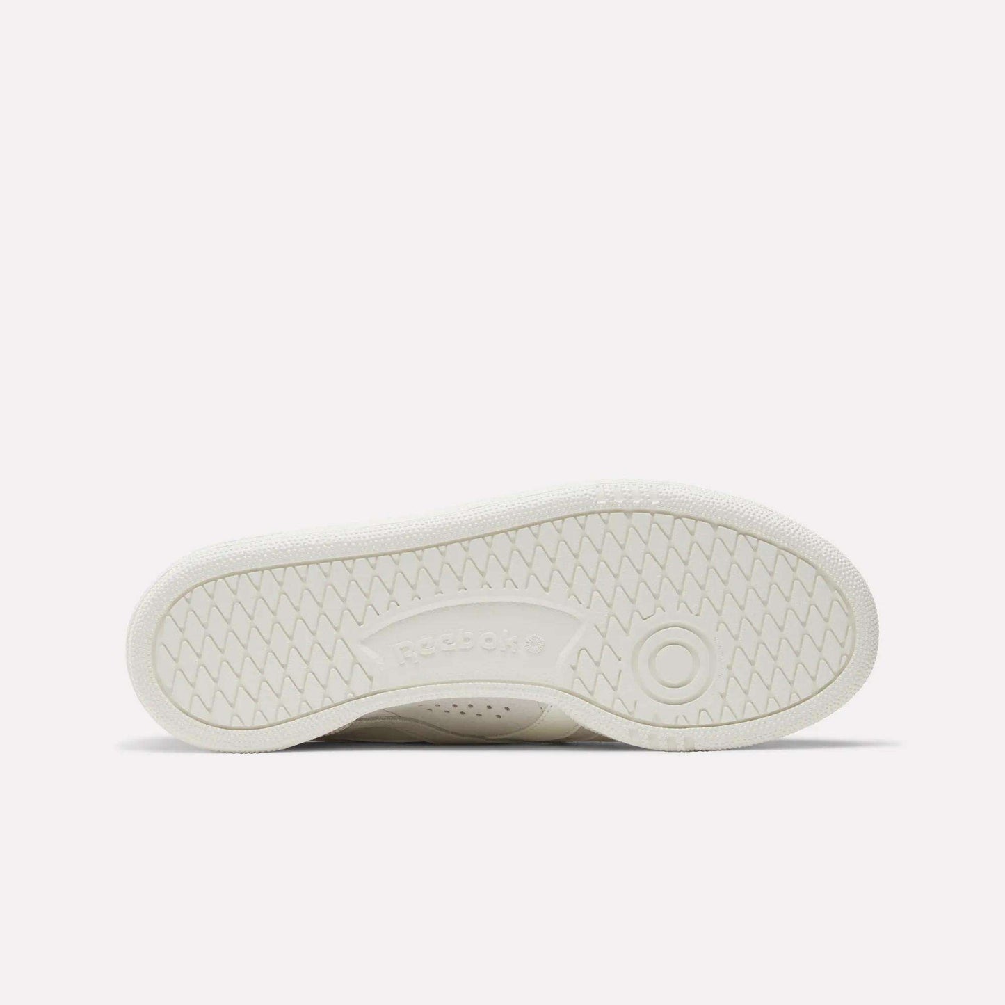 The image shows the white sole of the Reebok Women's Club C Grounds UK Shoes lying flat, with a herringbone tread pattern and an embossed Reebok logo at the center.