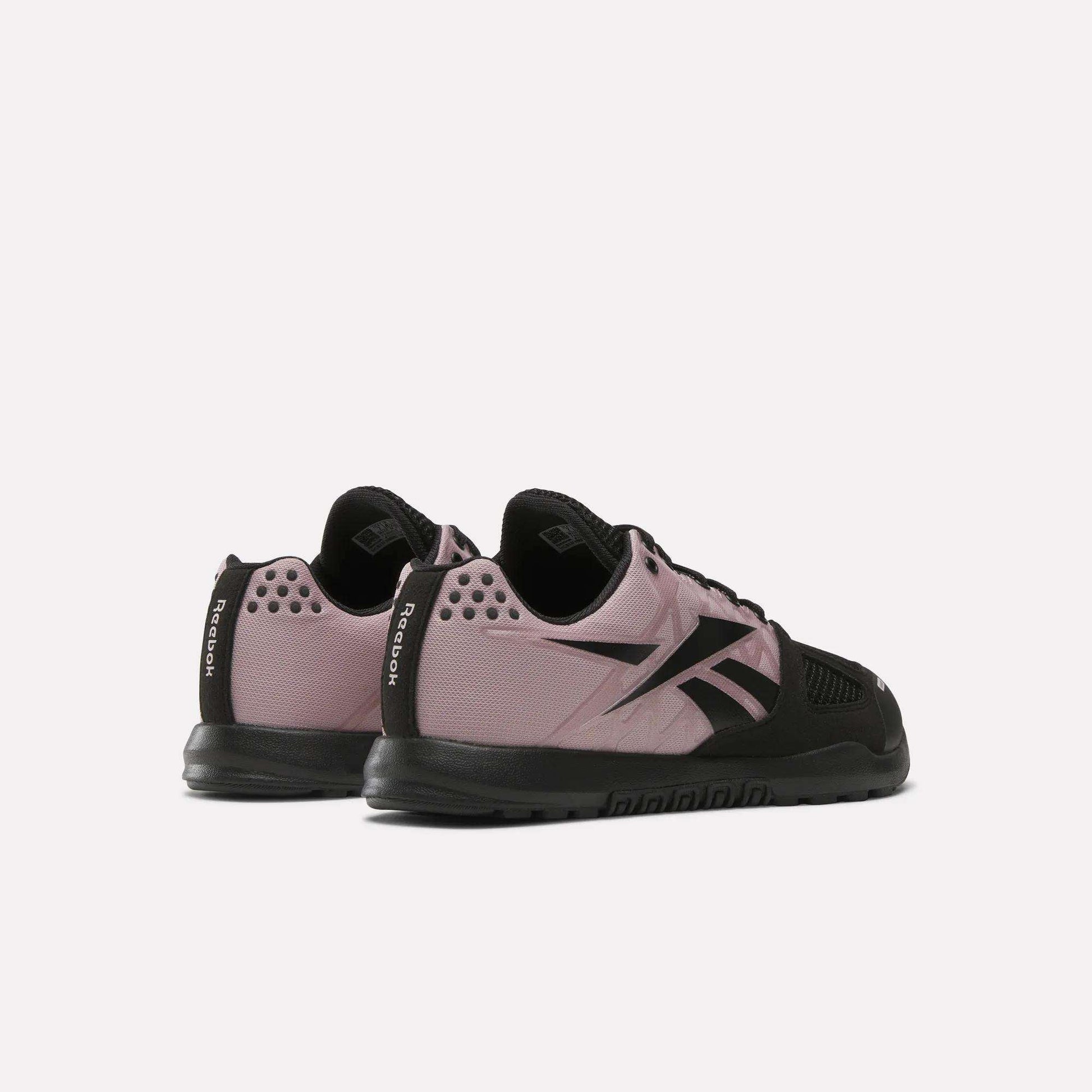 Reebok Women's Nano 2.0 Training Shoes in mauve and black are displayed on a light background with the heels angled together, showcasing their side and rear design—perfect for women's functional fitness routines.