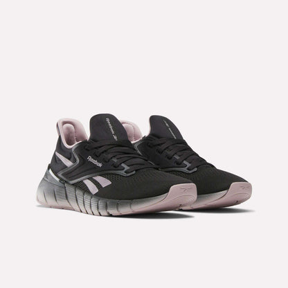 A pair of black and light pink Reebok Women's Nano Gym Training Shoes with mesh uppers, bold midsoles, and side logos are shown on a white background—ideal versatile footwear for any workout routine.