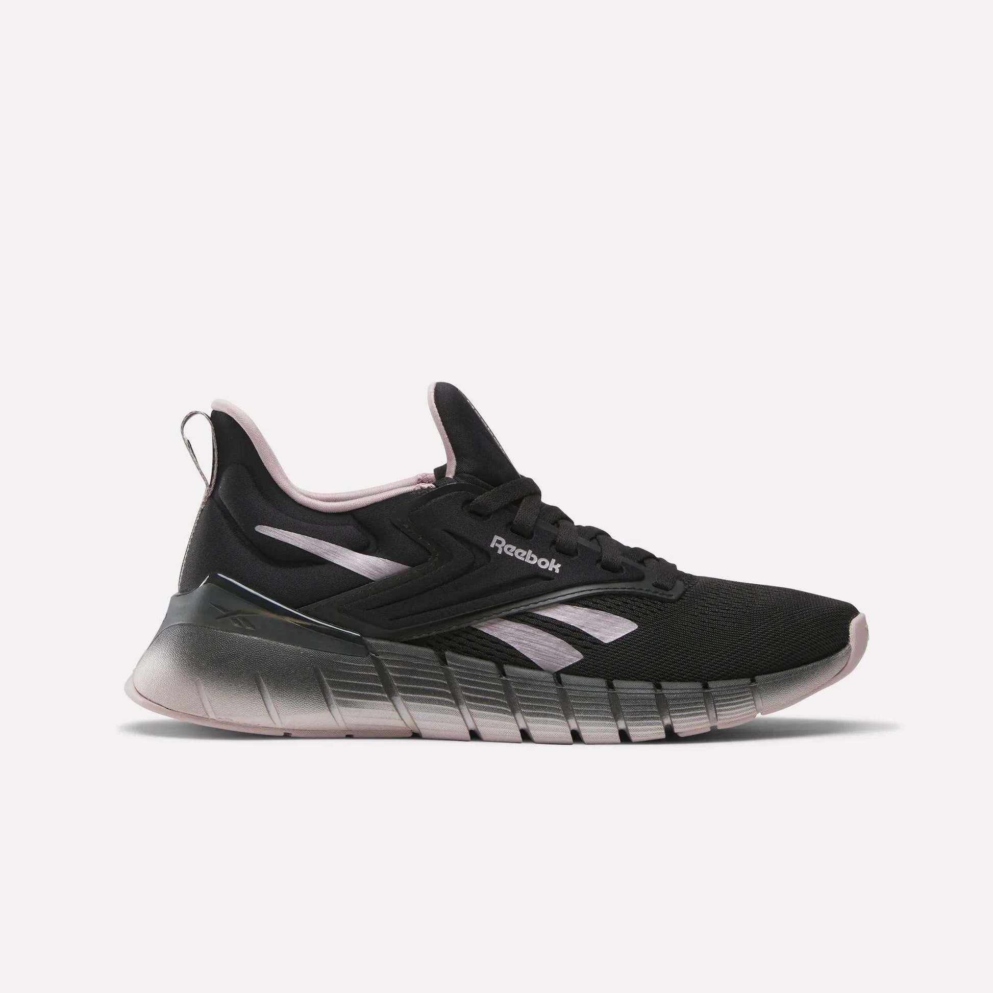 The Women's Nano Gym Training Shoes by Reebok feature a black design with light pink and white accents, a chunky gradient sole, and a low-top profile—ideal as versatile workout shoes for any fitness routine.