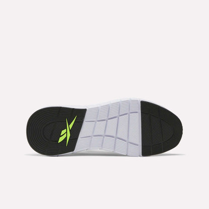 The image shows the sole of a white Reebok Men's Nano Gym Training Shoe with black heel and toe sections, a yellow-green Reebok logo near the heel, and a textured grid pattern—ideal for versatile workouts.
