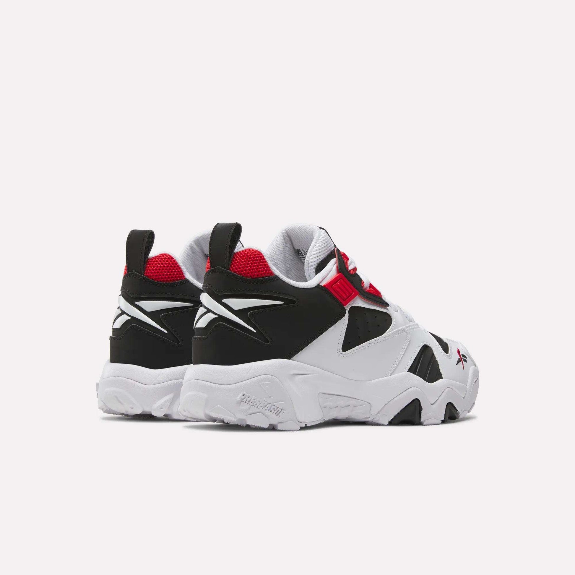 The Reebok Brutus Low Shoes in white, black, and red are shown angled to display chunky soles, red inner lining, and Reebok logos on the heel and side for a bold street-ready look.