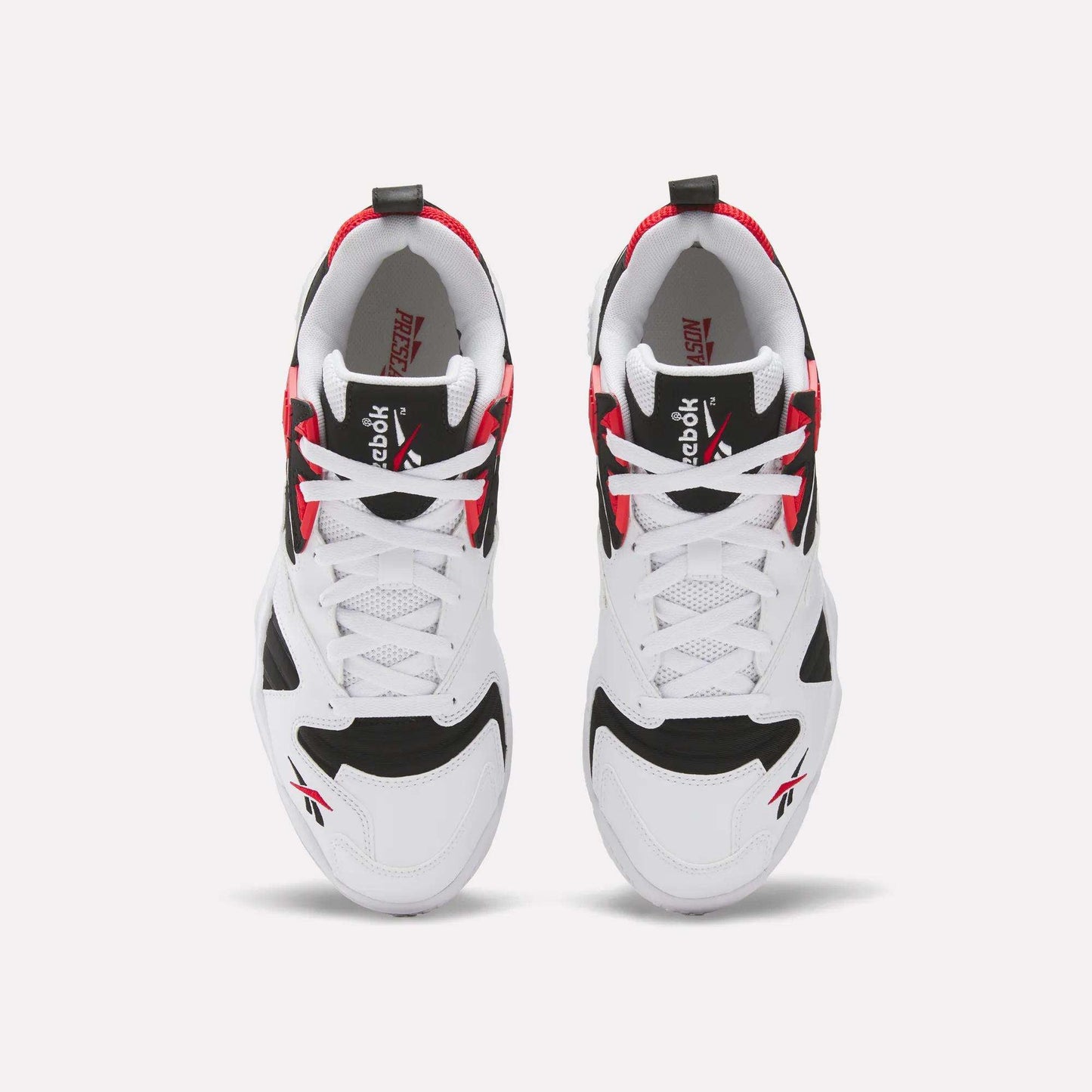 A pair of Brutus Low Shoes by Reebok seen from above, featuring a white base with black and red accents, white laces, and Reebok logos on the tongue and side—ideal for street-ready style.