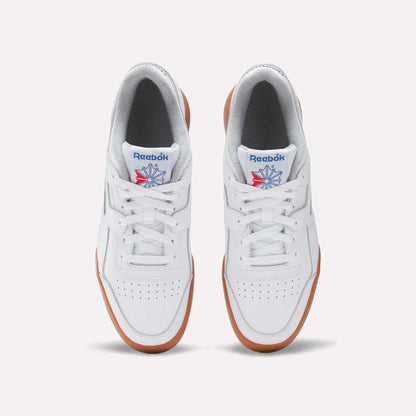 Top view of the Reebok Women's Workout Plus Shoes: classic white sneakers with brown gum soles, perforated toes, blue and red Reebok logos on the tongues, and a subtle '80s fitness vibe.