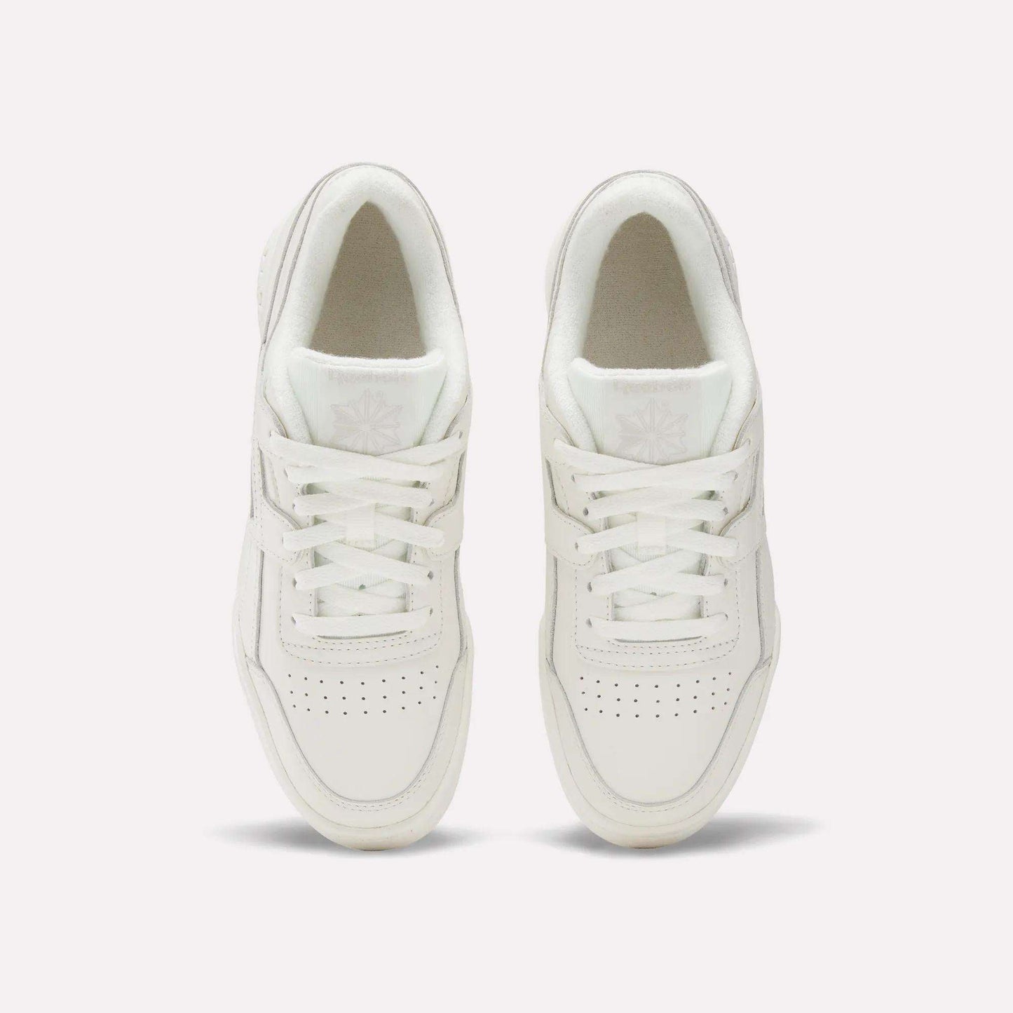 The Reebok Women's Workout Plus Shoes are shown from above on a plain white background, highlighting the laces, perforated toes, and logo details—ideal everyday workout sneakers.