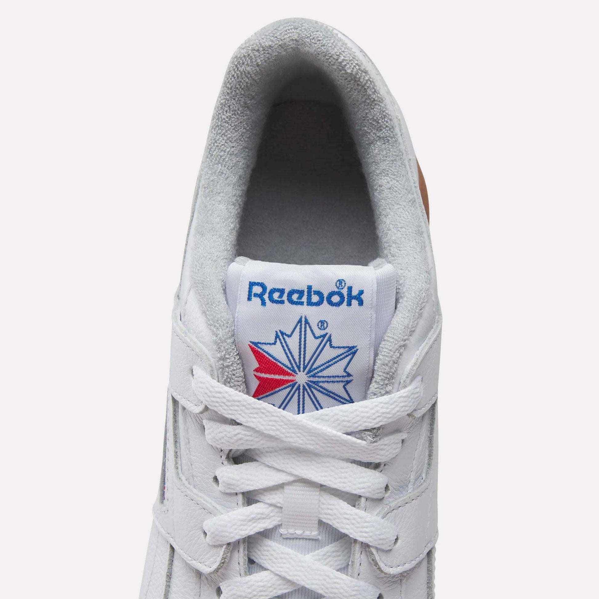 Top view of Reebok Workout Plus Shoes features gray lining, white laces, and a blue Reebok logo with a red and blue star on the tongue—a classic tribute to '80s fitness heritage.