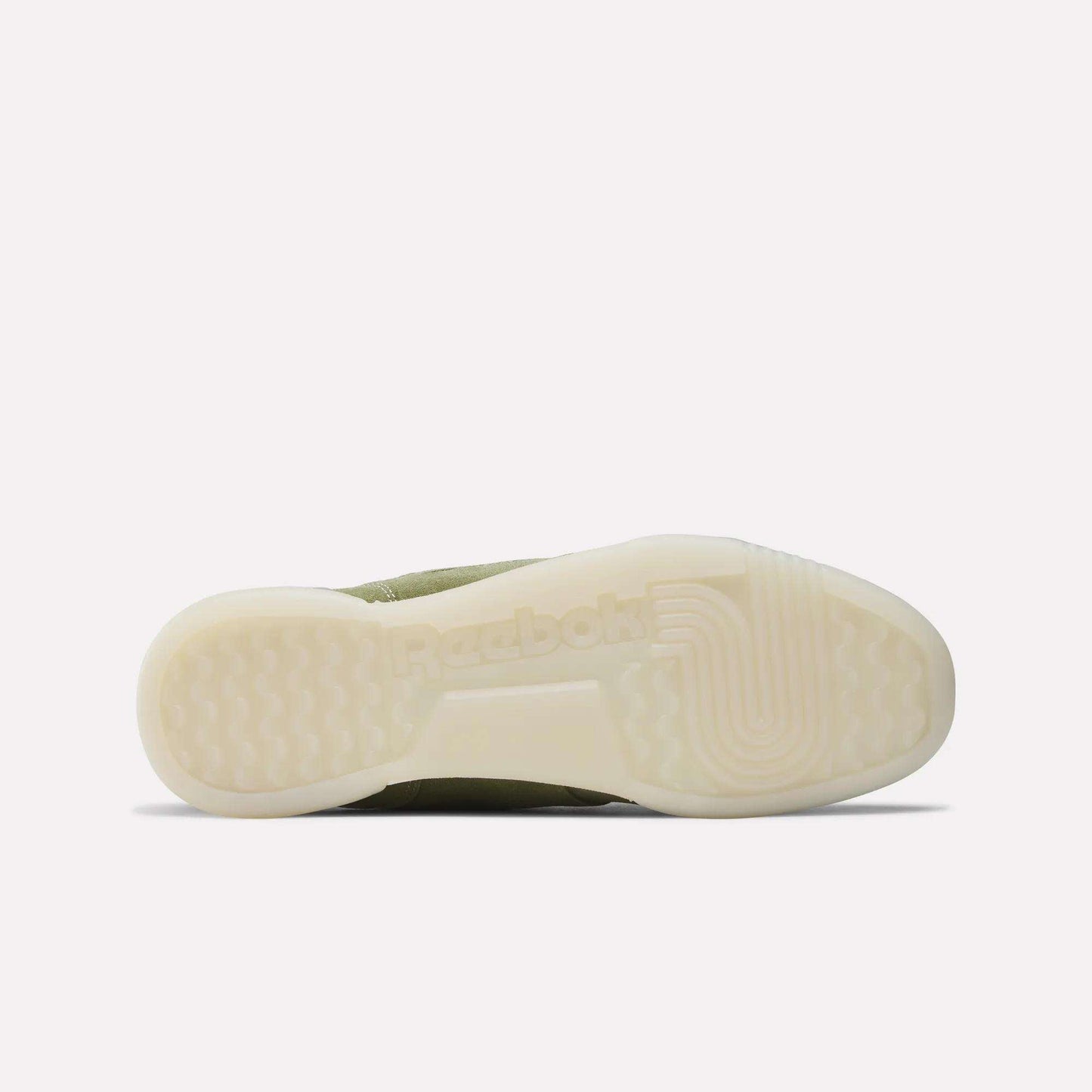 The image shows the bottom view of Reebok Workout Plus Shoes, featuring an off-white translucent sole with the Reebok logo and textured tread. The olive green upper adds to its classic '80s-inspired fitness style.