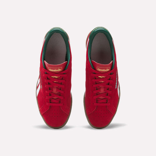 Top view of a pair of Reebok Club C Grounds UK Shoes in red with white side stripes, green inner lining, and gold branding on the tongue, displayed side by side on a white background—classic tennis-inspired casual style.