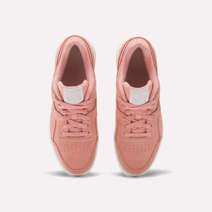 A pair of Women's Workout Plus Shoes by Reebok in pink with white soles, top view highlighting laces, perforated toes, and a white logo patch on the tongue—ideal for capturing vintage 80s workout style.