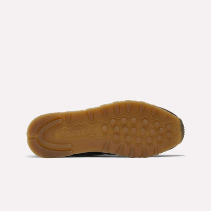 The image shows the bottom view of Reebok x C.F. Stead Classic Leather Shoes, featuring a brown rubber sole with circular treads and an embossed Reebok logo near the heel for a luxe design.